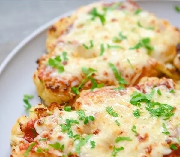 Cauliflower steaks drizzled with marinara sauce on a plate