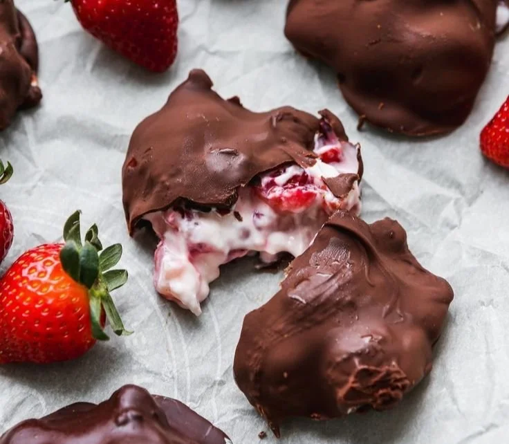 Delicious chocolate-coated strawberry yogurt clusters on a white plate