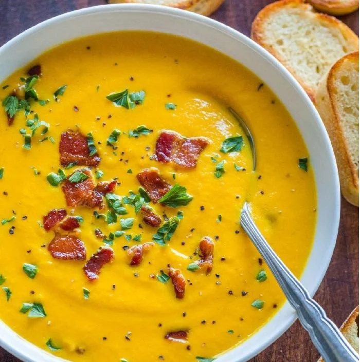 Delicious creamy carrot soup in a bowl garnished with herbs