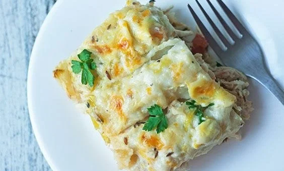 Light white chicken enchiladas topped with creamy sauce and fresh herbs
