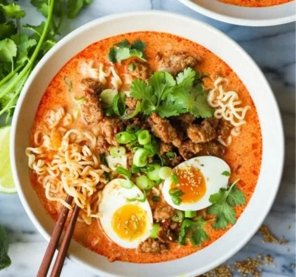 Delicious bowl of Thai Coconut Ramen Soup with fresh herbs and toppings